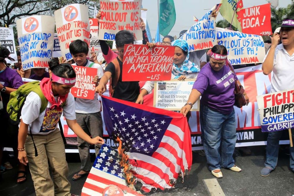 Protesters burn a US flag and pictures of incoming president Donald Trump outside the US embassy in Manila. Photo: Reuters