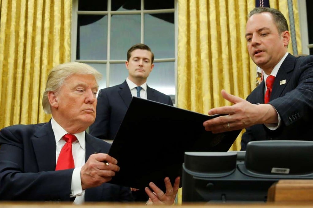 US President Donald Trump hands Chief of Staff Reince Priebus an executive order that directs agencies to ease the burden of Obamacare, after signing it in the Oval Office in Washington. Photo: Reuters