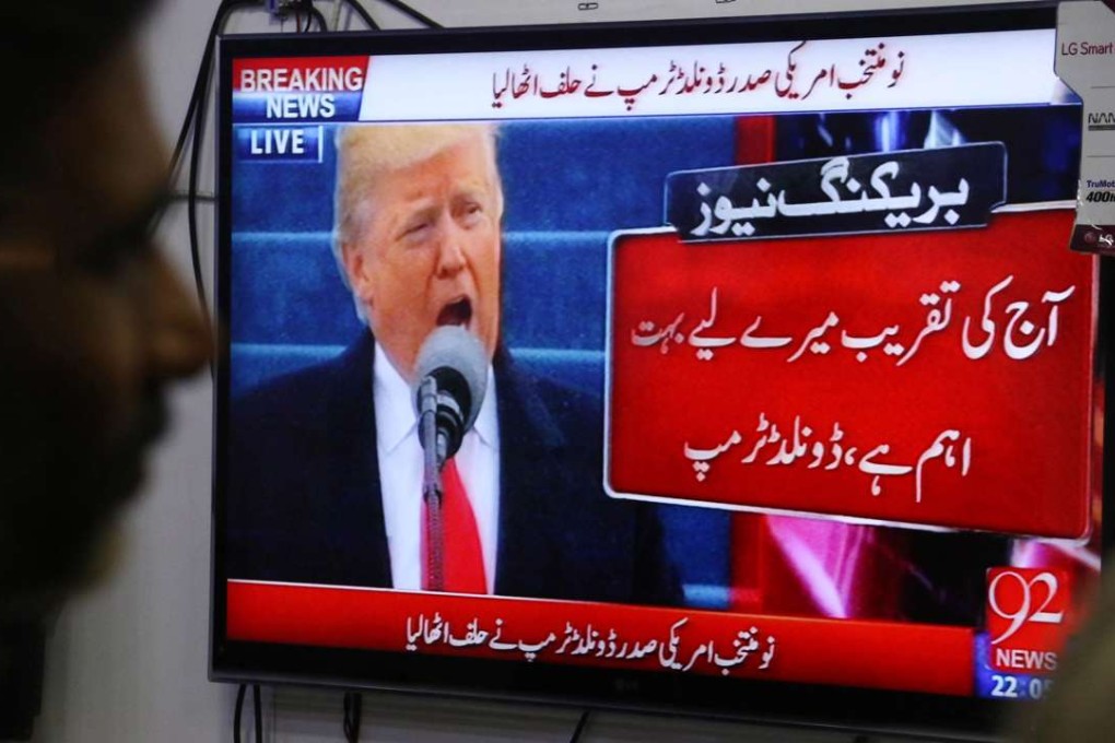A Pakistani man watches the news as Donald Trump takes the oath of office. Photo: EPA