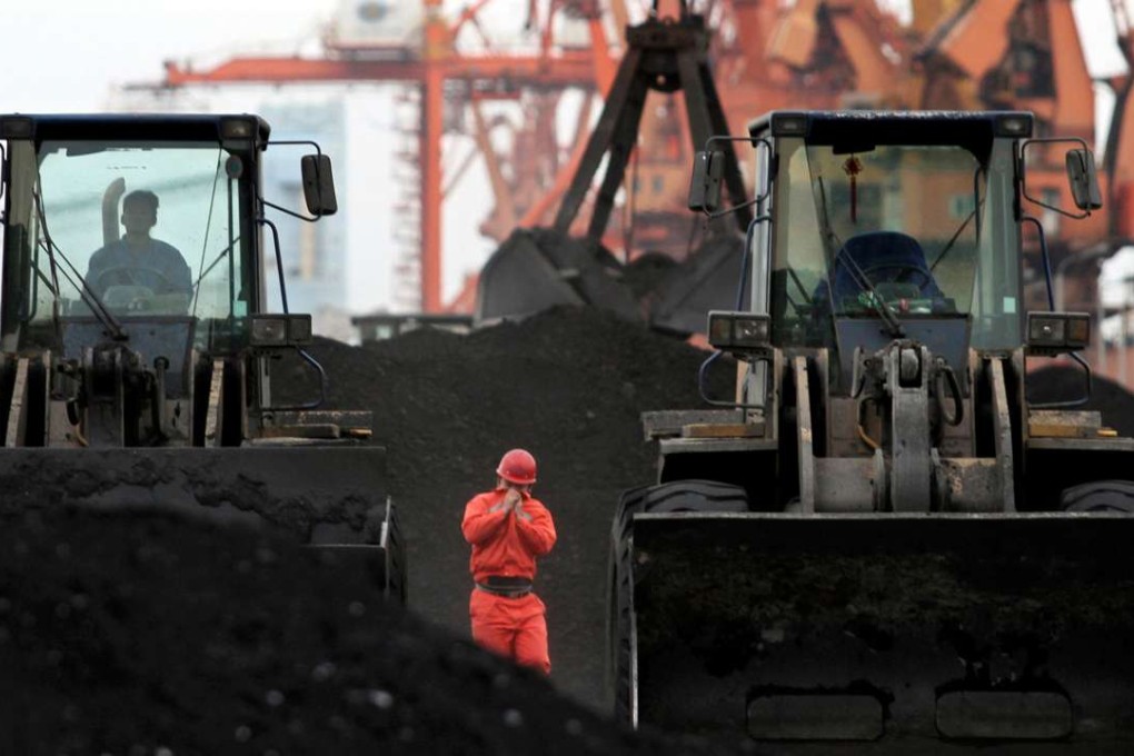 An employee walks between front-end loaders which are used to move coal imported from North Korea at Dandong port in Liaoning. Photo: Reuters