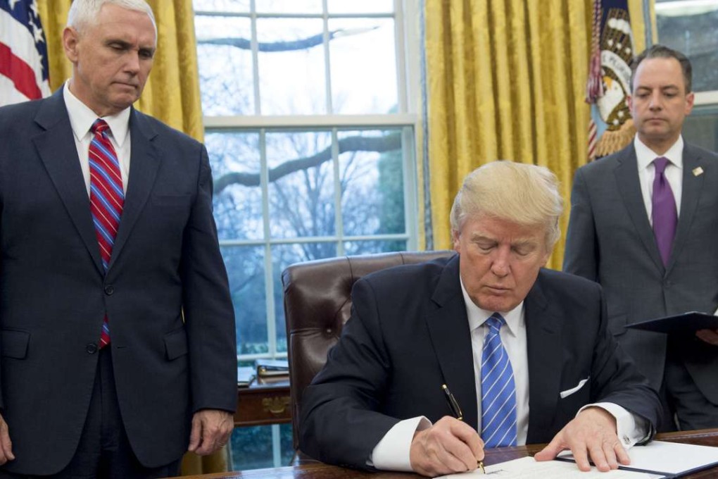 US President Donald Trump signs an executive order withdrawing the US from the Trans-Pacific Partnership. Next to him are US Vice President Mike Pence, left, and White House Chief of Staff Reince Priebus. Photo: AFP