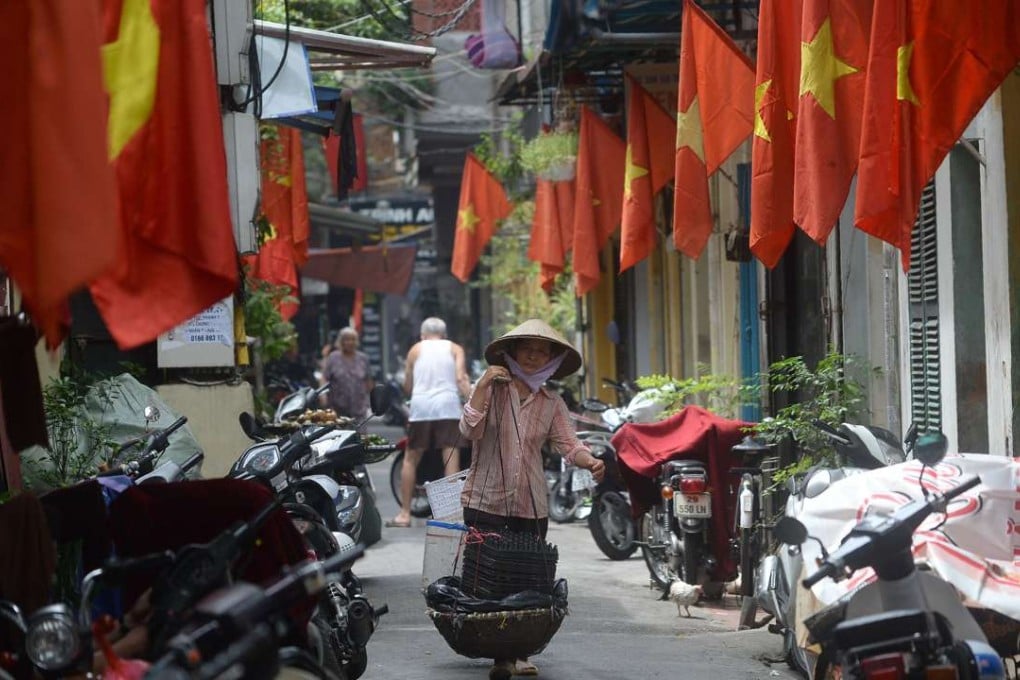 A street vendor walking past rows of Vietnamese national flags hung in front of homes. Photo: AFP