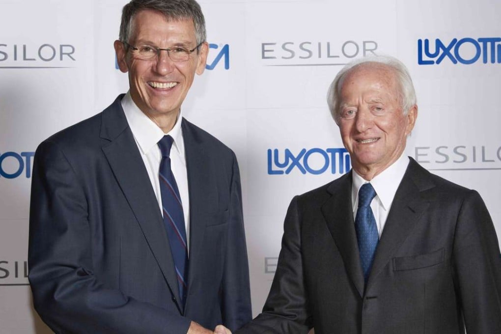 Founder and chairperson of Italian eyeglass producer Luxottica Leonardo Del Vecchio (R) shaking hands with CEO of French lens maker Essilor Hubert Sagnieres in Paris. French lensmaker Essilor has agreed to buy Italy's Luxottica, maker of Ray-Ban sunglasses, in a bid to create a new global giant in the sector. PhotoL AFP