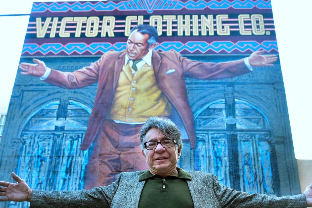 Muralist Eloy Torres mimicks the pose of Oscar-winning Actor Anthony Quinn on the 70-foot-tall "Pope of Broadway" mural he helped restore after years of deterioration during a ceremony in downtown Los Angeles. Photo: AFP