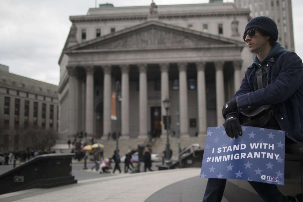 A demonstrator holds a sign outside New York Sate Supreme court before taking part in Jummah, a Muslim Friday prayer service, in Foley Square, New York City. Photo: AP
