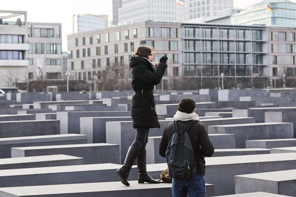 Visitors take photos while standing on the blocks of the Memorial to the Murdered Jews of Europe in Berlin last Thursday. Photo: EPA