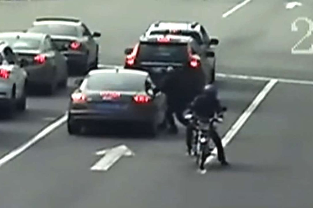 One of the thieves smashes the car window to steal the handbag at traffic lights in Foshan as his accomplice waits on the motorbike. Photo: Handout