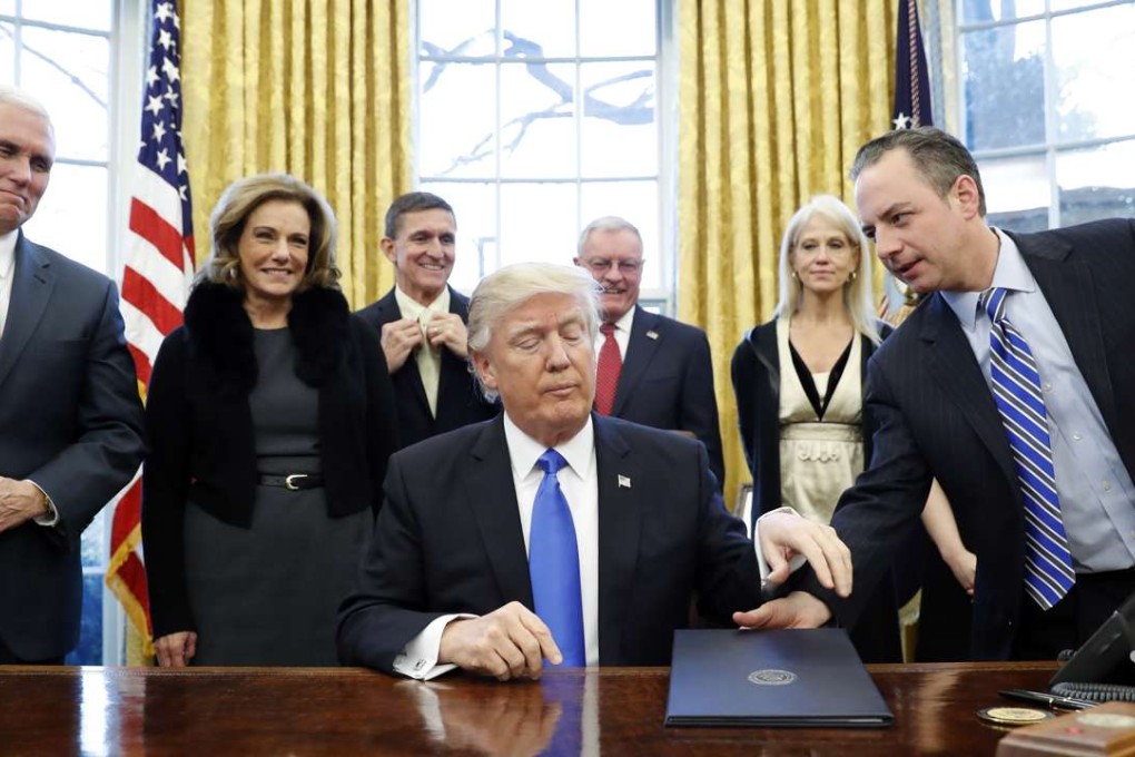 President Donald Trump is handed an Executive Order to sign by White House Chief of Staff Reince Priebus, right, with Vice President Mike Pence, left, and others nearby, in the Oval Office of the White House. Photo: AP