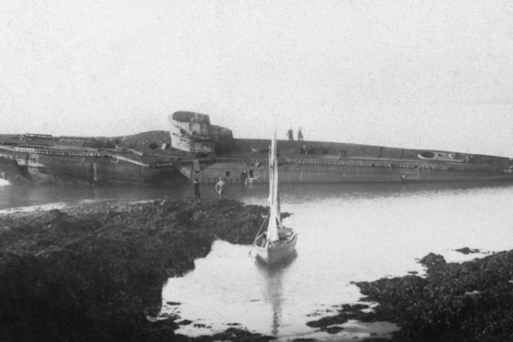 UB-112 on the rocks with a sail boat in the foreground and visitors on board. Photo: Historic England