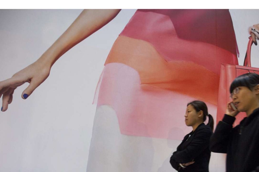 People walk past an advertising hoarding outside a Fendi luxury leather goods store, in Hong Kong.
