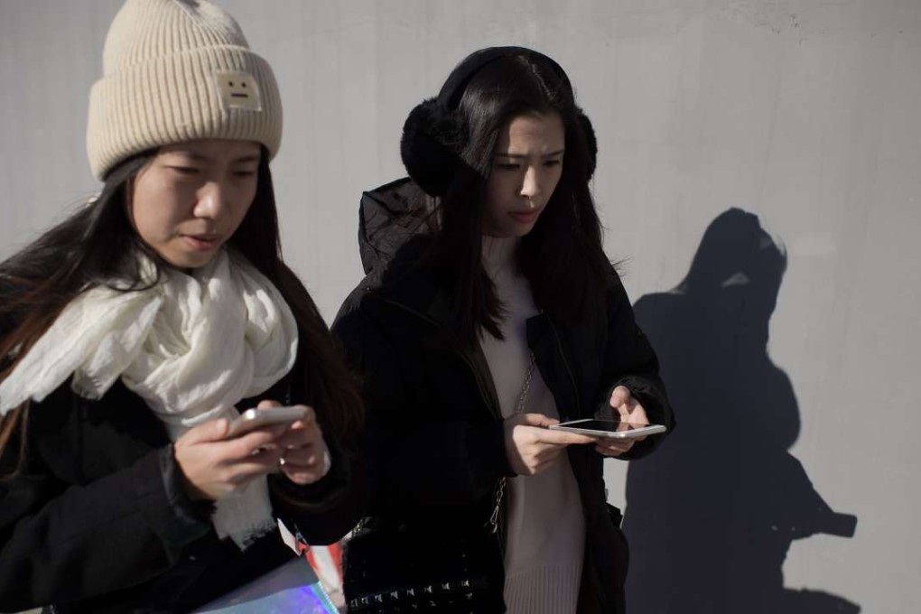 Two young women using their smartphones in Beijing. Photo: AFP