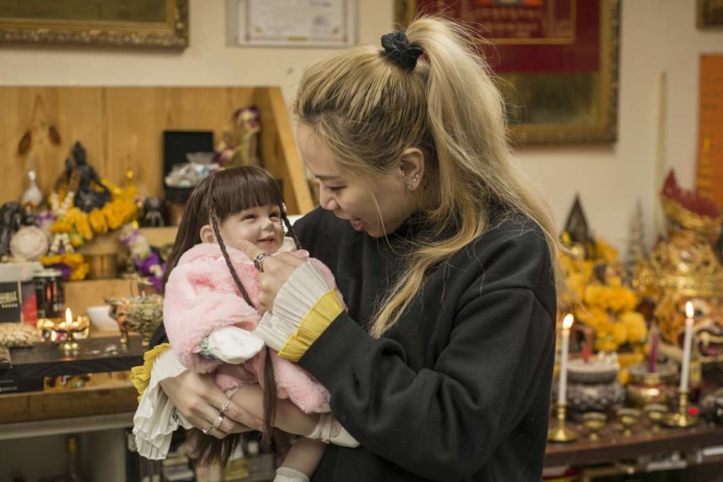 Proprietor Cat holds a doll named Tung Tung, which is said to contain the spirit of an aborted fetus, at her store in Kwun Tong. Photos: Antony Dickson