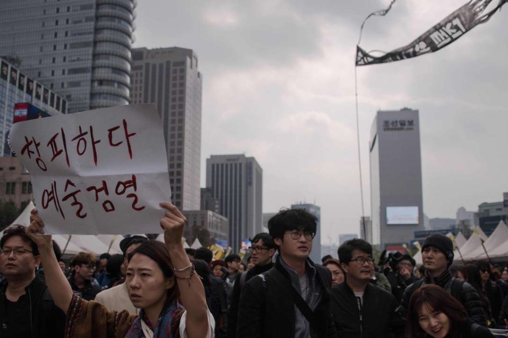 A woman standing with a group of artists holding a placard reading 'Shame on censorship' as they face off with police during an anti-government demonstration in central Seoul. Photo: AFP