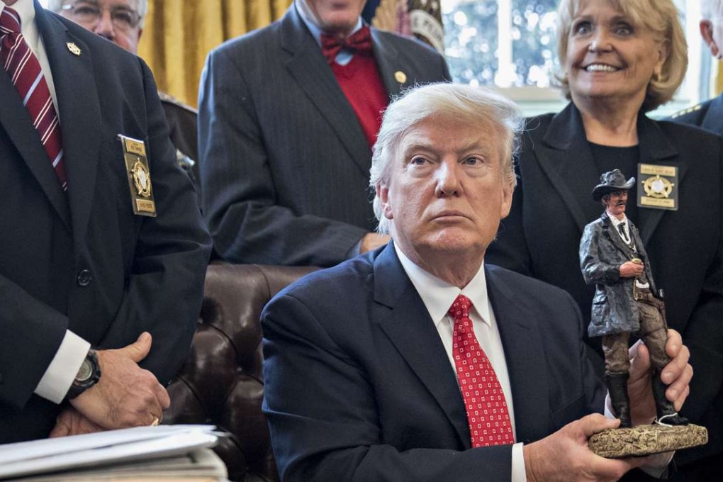 US President Donald Trump holds up a statue he received as a gift while meeting with county sheriffs in the Oval Office of the White House in Washington, DC. Photo: Bloomberg