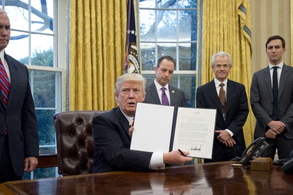 US President Donald Trump holds up an executive order marking American withdrawal from the Trans-Pacific Partnership in the Oval Office on January 23, as key members of his White House inner circle, including National Trade Council chief Peter Navarro (second right), look on. Photo: Bloomberg