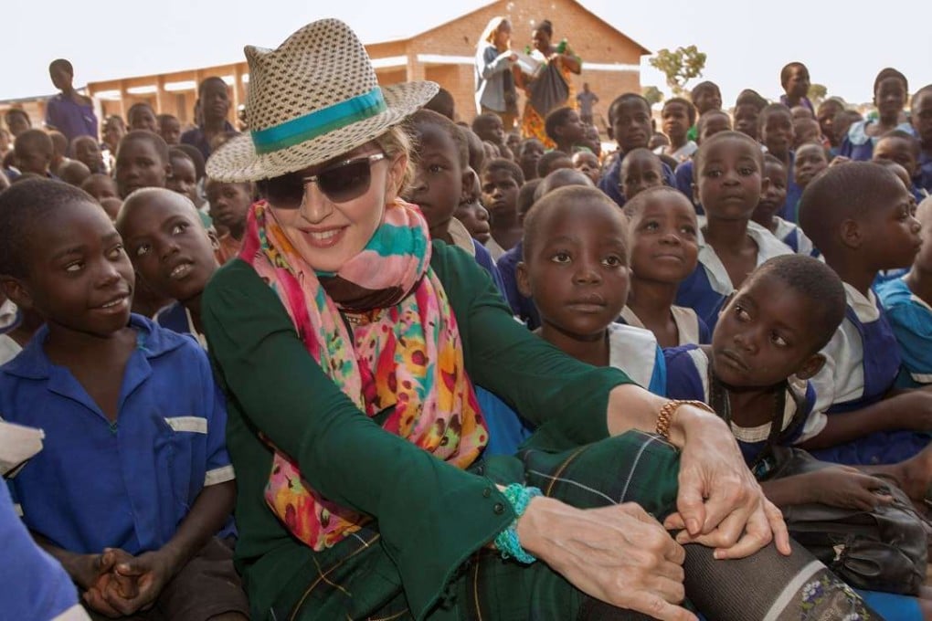 This file photo taken on November 30, 2014, shows US pop superstar Madonna sitting among Malawian children during a visit to the Mkoko Primary School, one of the schools Madonna's Raising Malawi organisation has helped build in the Kasungu District of central Malawi. Photo: AFP