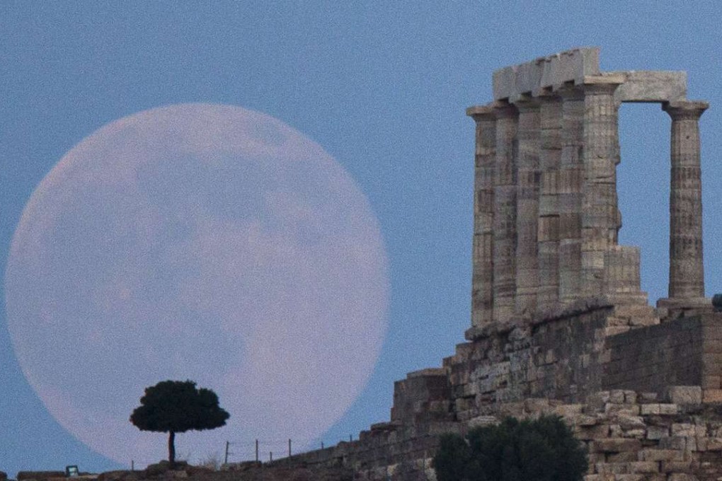 The full moon rises behind a tree next to the ruins of the ancient marble Temple of Poseidon, built in 444 BC, at Cape Sounion, southeast of Athens. Photo: AP
