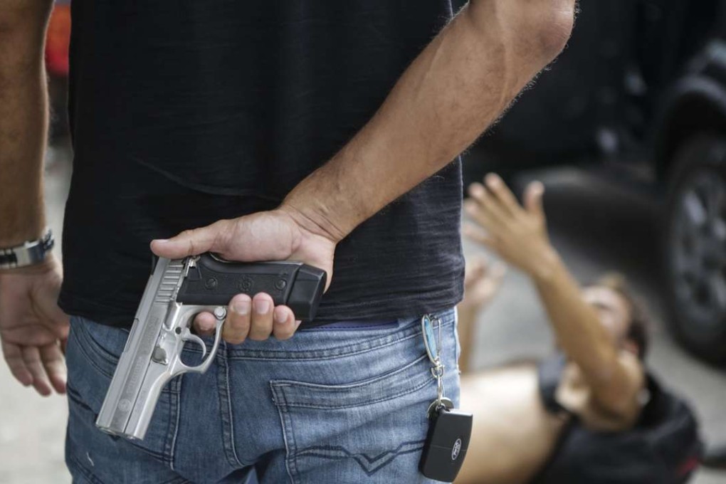 A civil police officer stands guard over a looter, shot in the leg, at an electronic store in Vitoria, Espirito Santo state, in Brazil on Monday. Photo: AP