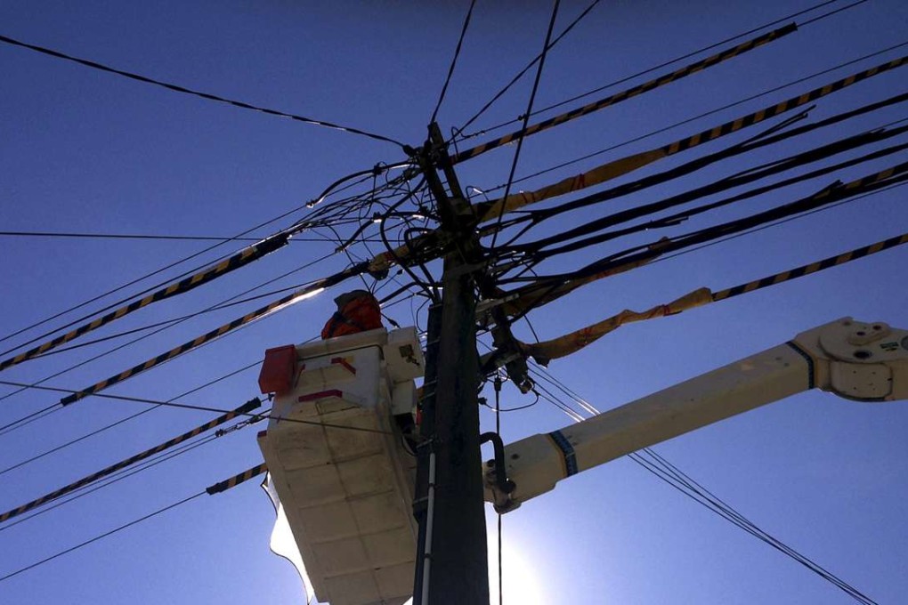 A worker stands in a crane as he fixes electricity cables in Sydney, Australia. Photo: Reuters