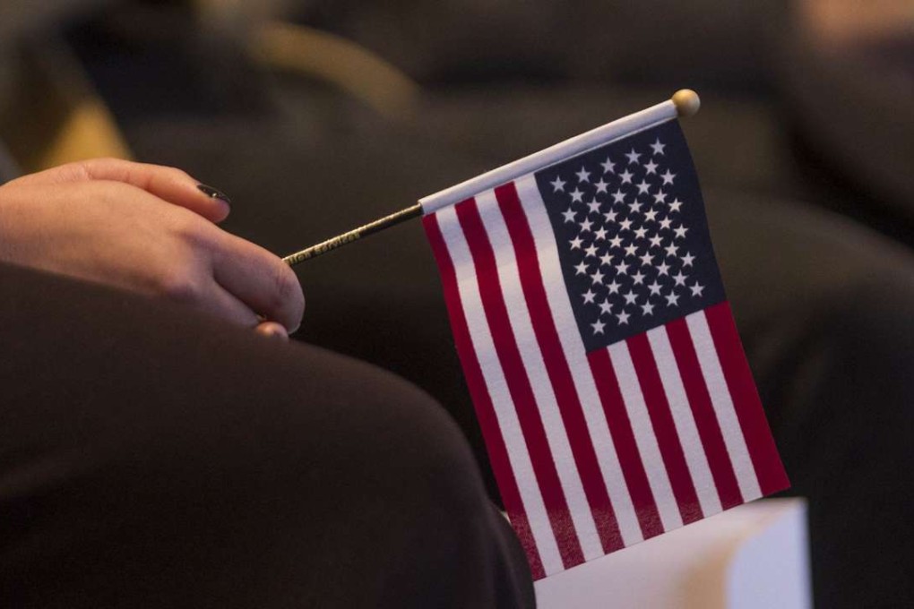 A woman holds an American flag during a Naturalization Oath Ceremony at the John F. Kennedy Presidential Library and Museum in Boston, Massachusetts. Photo: AFP