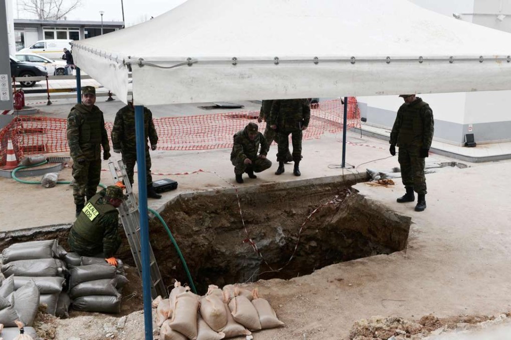 Military personnel of the Hellenic Army Explosive Ordnance Disposal (EOD) team stand at the site of a wartime bomb. Photo: AFP