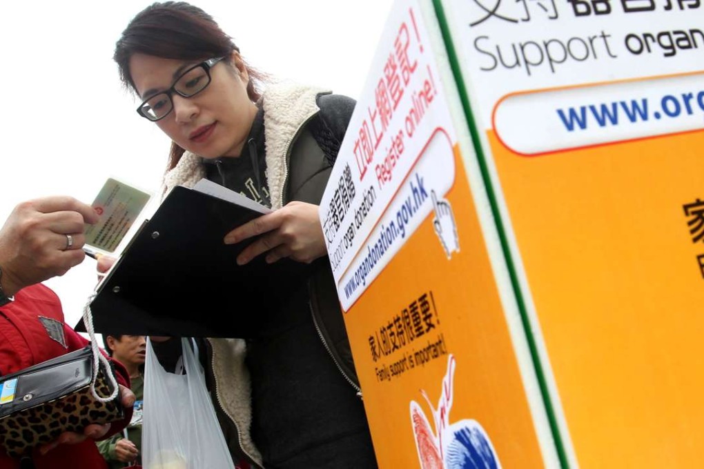 Members of the public sign a donation card during a promotional activity for organ donation by the Department of Health at Victoria Park. Photo: Felix Wong