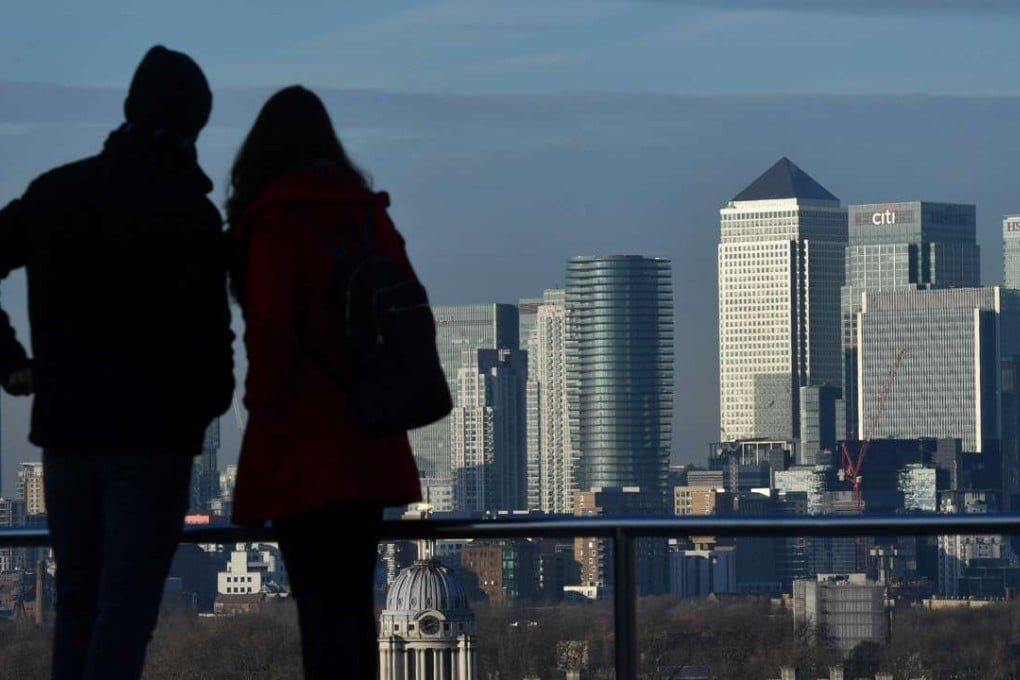 People stand and look out towards the financial offices of banks and other institutions in the financial district of Canary Wharf, from Greenwich Park in London. Photo: AFP