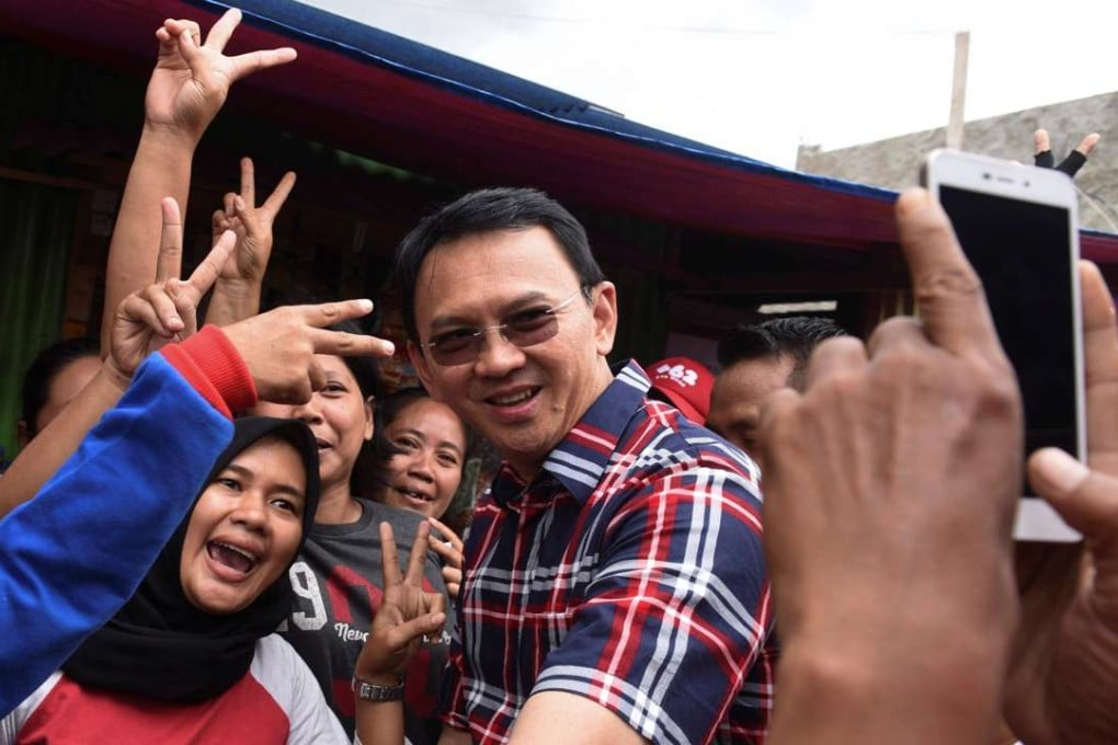 Jakarta governor Basuki Tjahaja Purnama take pictures with residents during his campaign. Photo: Reuters