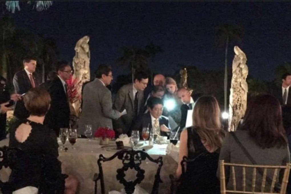 A photo posted on social media by a fellow diner shows aides crowding around Japanese Prime Minister Shinzo Abe, as he attempts to read documents by cellphone light, as he dines with Donald Trump at the Mar-a-Lago resort on Saturday night. The two leaders had just been told that North Korea had fired a missile towards Japan. Photo: Facebook / Richard DeAgazio