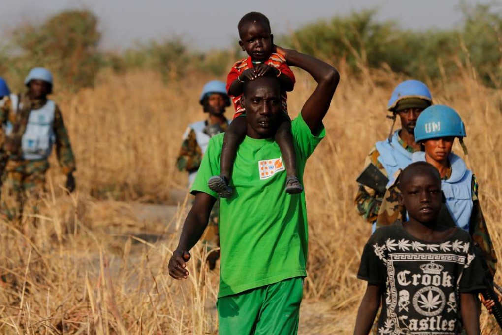 A man carrying his child walks past United Nations Mission in South Sudan peacekeeping soldiers on patrol near the town of Bentiu, in Rubkona county, northern South Sudan. Photo: Reuters