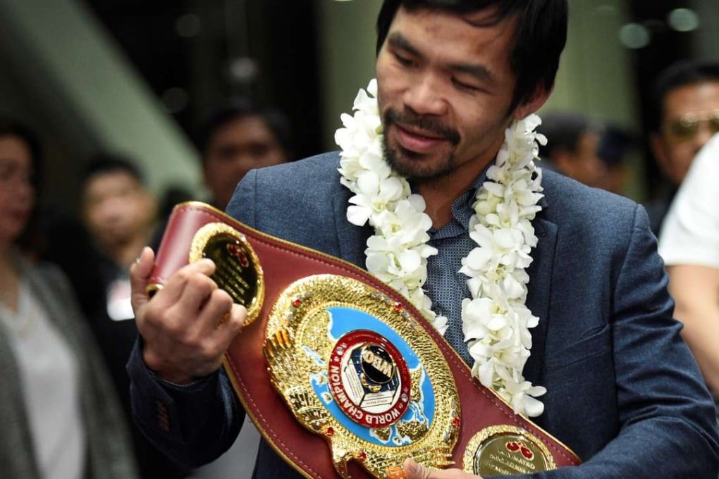 Manny Pacquiao holding up his welterweight title belt upon his arrival at the airport in Manila in November 2016. Photo: AFP