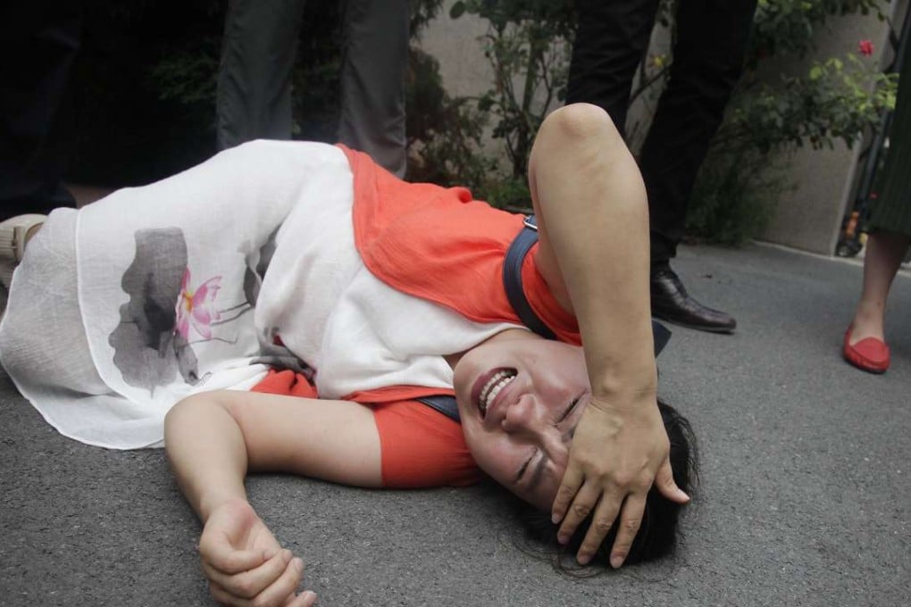 Fan Lili, the wife of imprisoned lawyer Gou Hongguo, lies on the ground in tears following interaction with a plainclothes police officer outside a courthouse in Tianjin last year, Human rights lawyers are being increasingly persecuted in China, according to the Network of Chinese Human Rights Defenders. Photo: AP