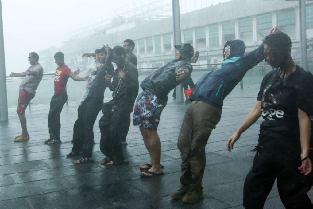 People brave the strong winds in Tsim Sha Tsui last October as Typhoon Haima hits Hong Kong. The consequences of global warming are not limited to extreme weather conditions or the increasing frequency and intensity of heat waves and cold spells that the media tends to focus on. Photo: Edmond So
