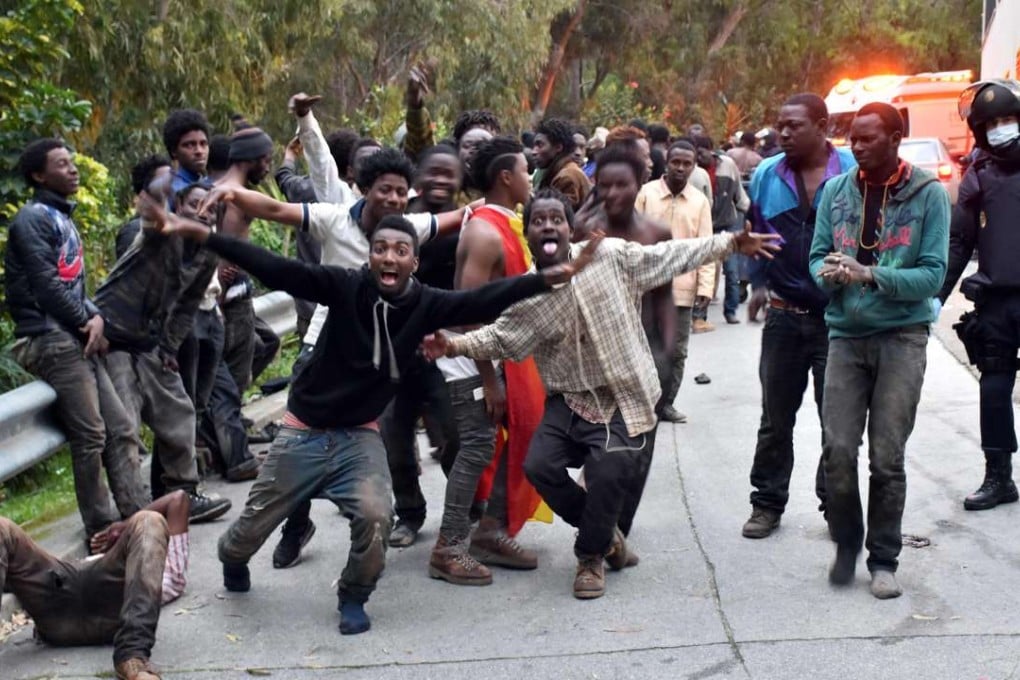 Migrants celebrate outside the Center for Temporary Stay of Immigrants (CETI) after forcing their way through a border fence. Photo: AFP
