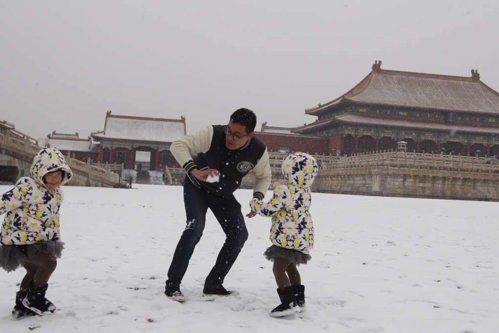 Mr Zhang plays in the snow at the Palace Museum with his twin daughters on Tuesday. Photo: Simon Song