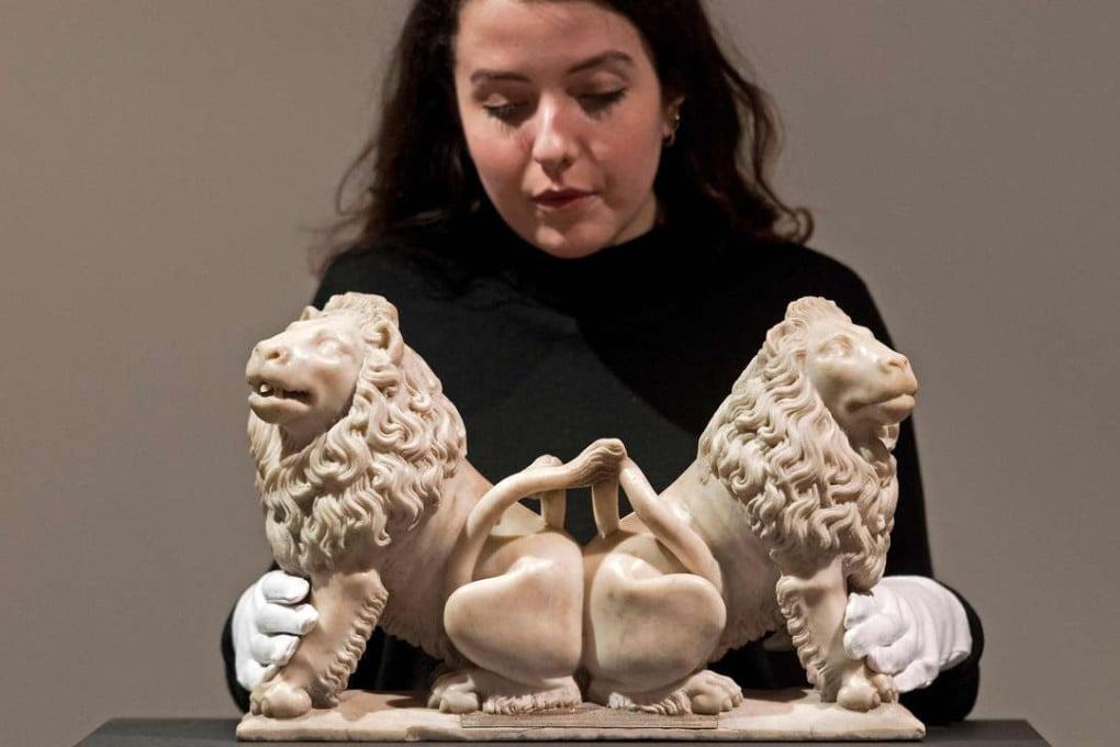 An employee of auction house Christie’s poses with a sculpture of two carved marble lions, by French artist Andre Beauneveu, commissioned by French King Charles V. Photo: AFP