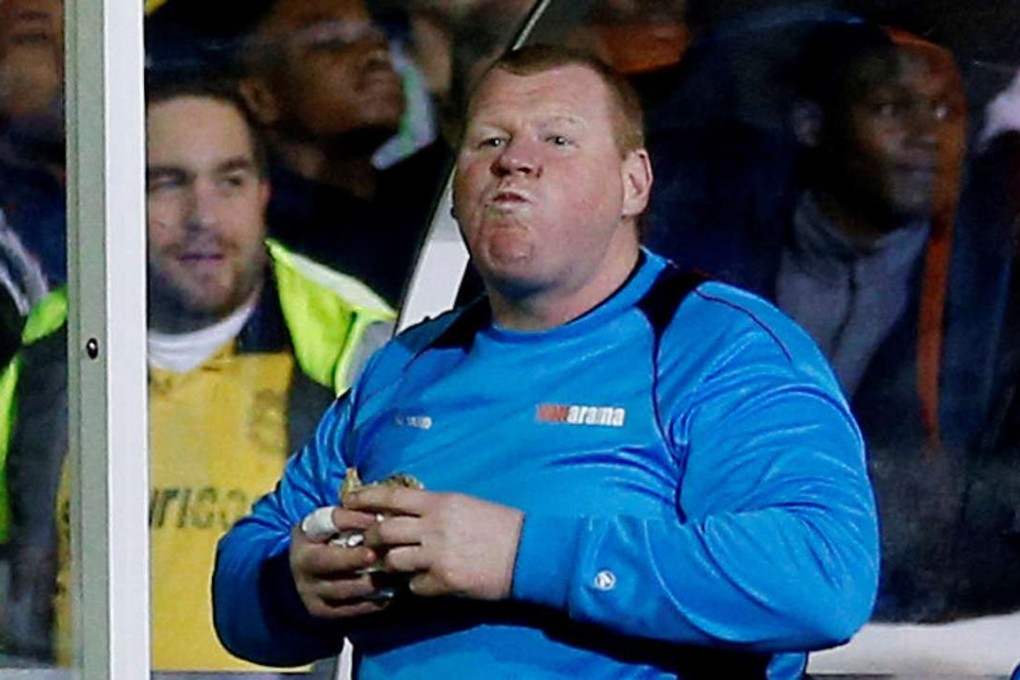 Sutton United reserve goalkeeper Wayne Shaw tucks into a pie during the match. Photo: Reuters