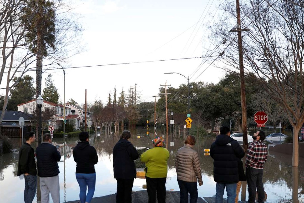 People stand by a flooded street near William Street Park after heavy rains overflowed nearby Coyote Creek in San Jose, California. Photo: Reuters