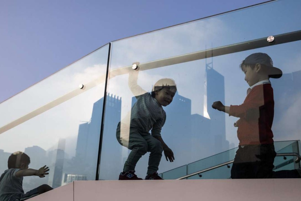 Children play on a viewing platform in Hong Kong as the city’s skyline is reflected in the glass panels. Hong Kong has long been a centre for processing questionable money flows. As a major financial player, it is under pressure to be truly compliant with global governance norms. Photo: AFP