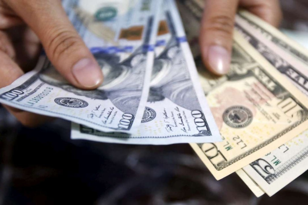 A bank employee checks US dollar bank-notes. Photo: Reuters