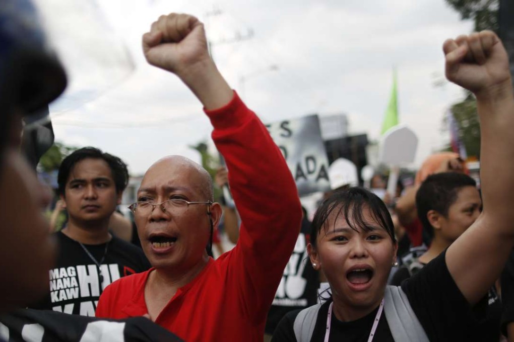 Members of a group called Block Marcos Movement shout slogans during a demonstration to mark the 31st anniversary of the People Power Revolution. Photo: EPA
