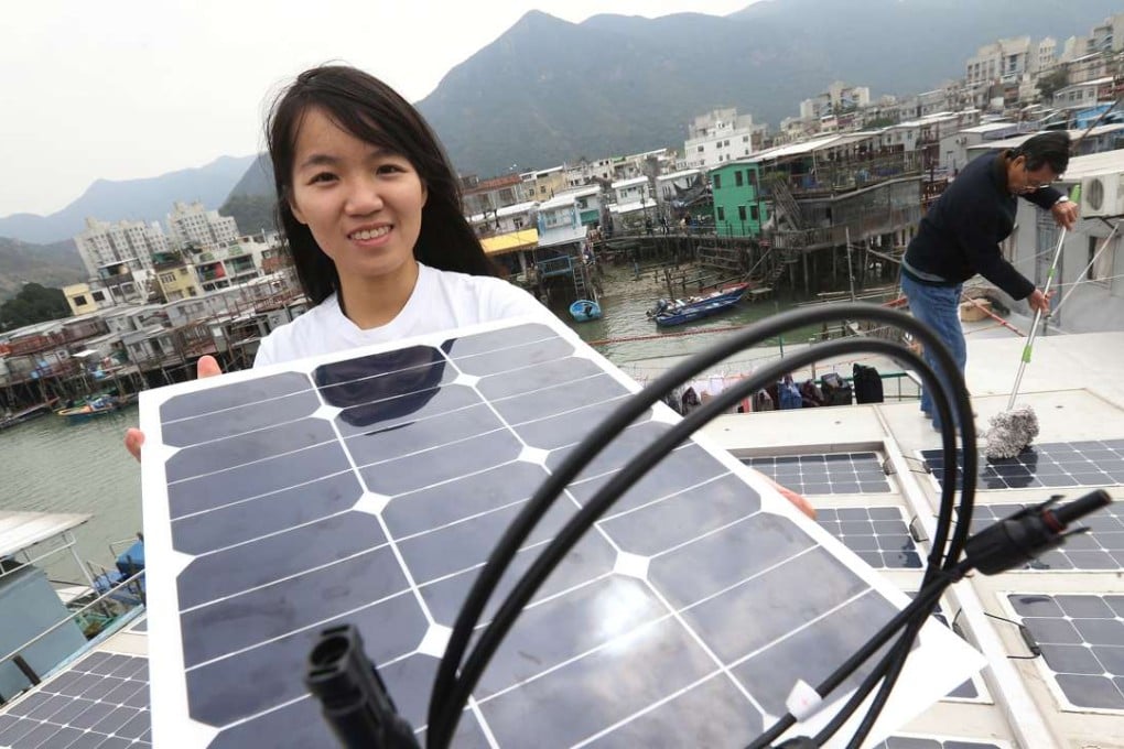 WWF-Hong Kong public engagement officer Olivia To Pui-wai (front) and Tai O resident Leung Ming-chi tend to solar panels on Sunday on the roof of a house in the Lantau fishing village. Photo: Dickson Lee