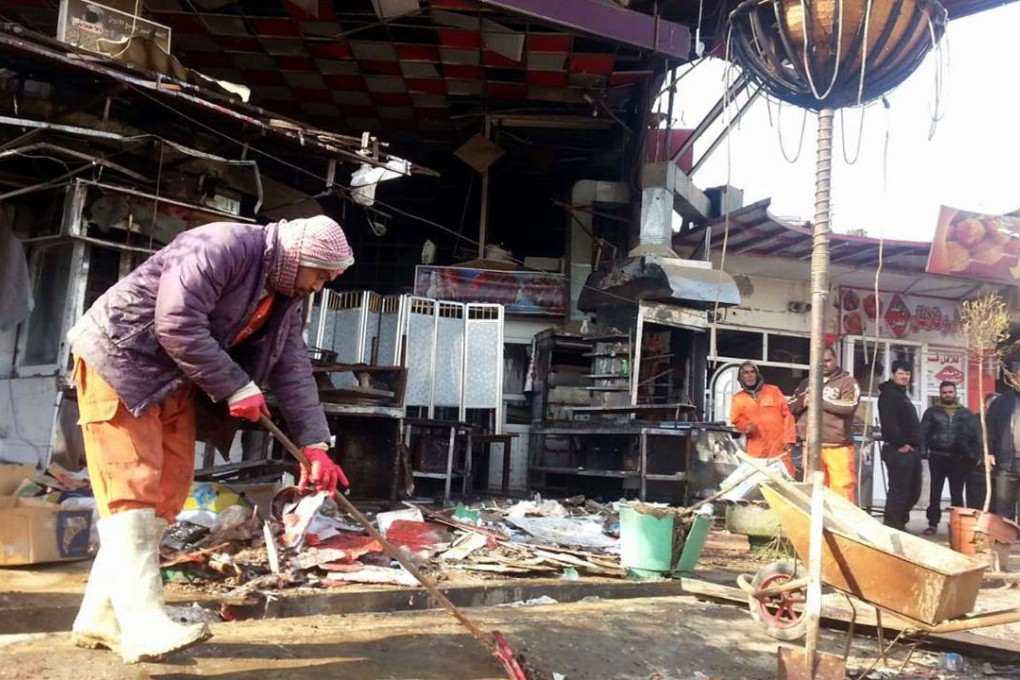Iraqi workers remove debris from the aftermath of suicide bomb attack in eastern Mosul on February 11. Photo: EPA