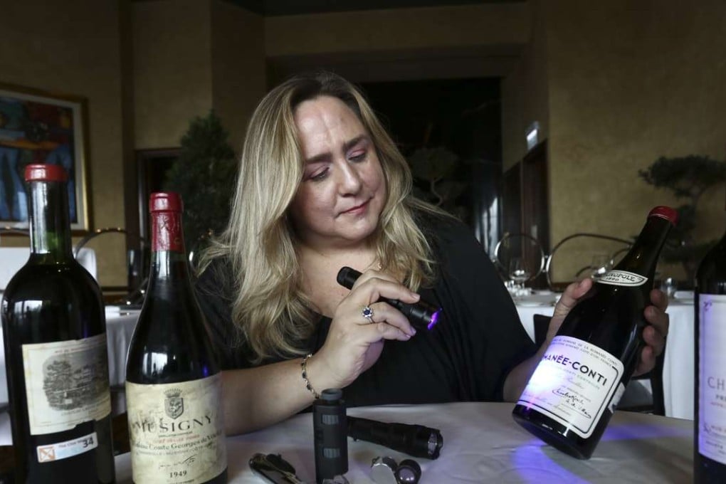 Maureen Downey shows how she uses a blue light to check the age of the paper used on labels, on a this bottle of fake Romanée-Conti. Photo: Jonathan Wong