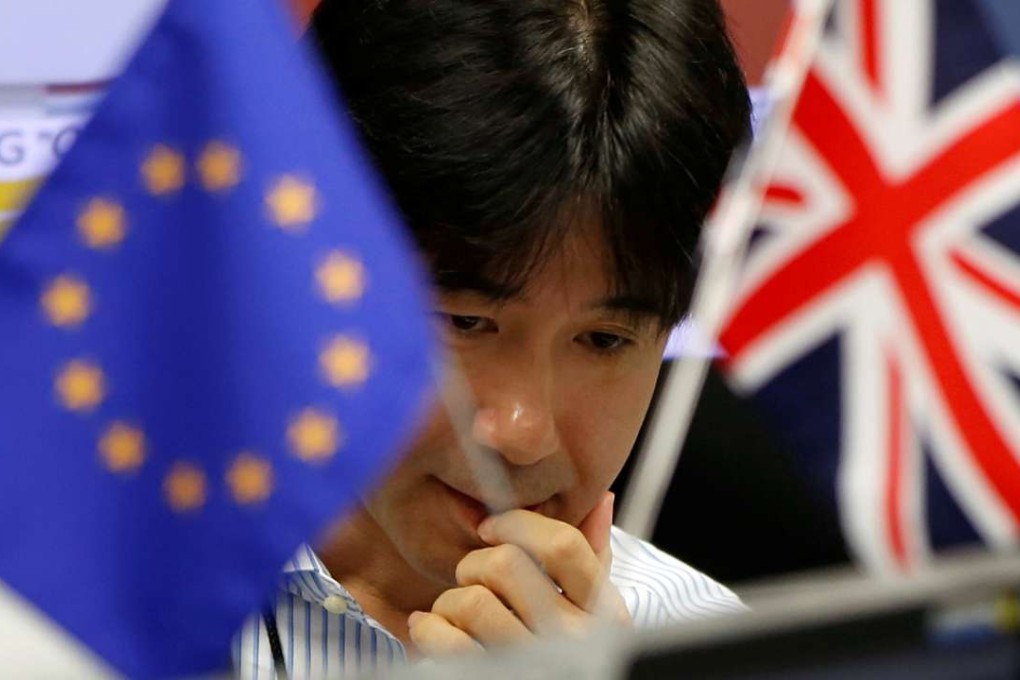 A foreign exchange worker in Tokyo, pictured between the European and British flags. Photo: Reuters