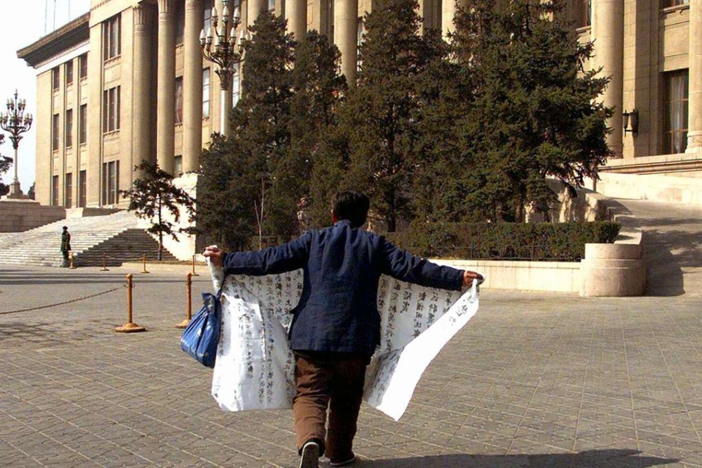 A protester unveils his petition as he walks to the steps of the Great Hall of the People in Beijing on Thursday. China's annual meeting of the Chinese People's Political Consultative Conference began on Friday ahead of the National People's Congress on Sunday. Photo: AFP