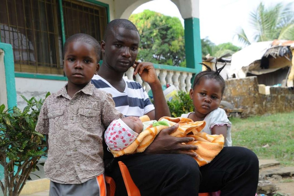 James Harris, the husband of Salome Karwah, sits with his children in his home in Monrovia. Photo: AFP