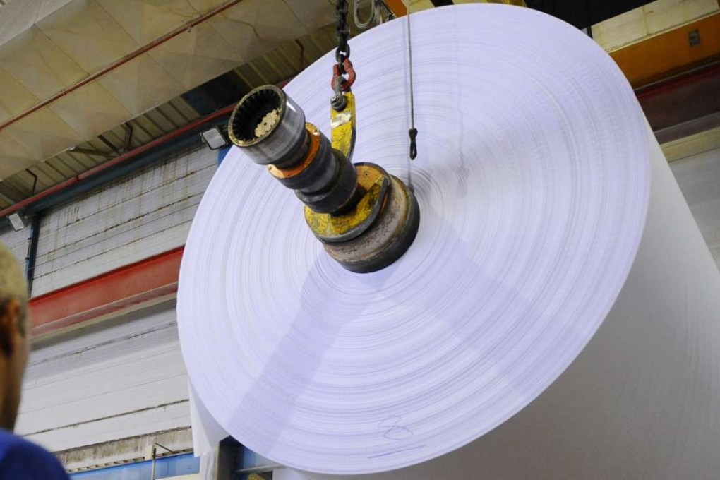 A worker inspects paper at a factory. Rising demand is pushing producer prices higher. Photo: AFP