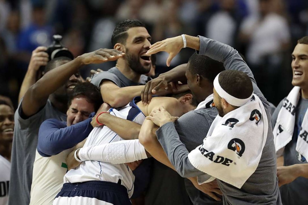 Dirk Nowitzki is mobbed after scoring his 30,000 career point with Mark Cuban and his team. Photo: AP