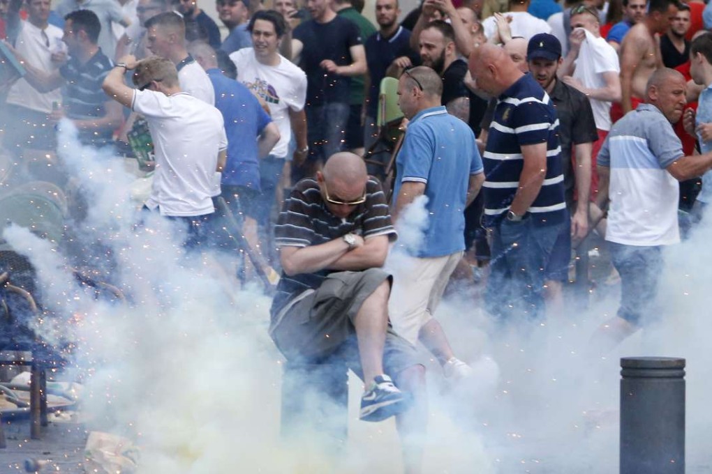 An England fan evades a smoke grenade thrown by riot French police during clashes with Russian supporters. Photo: EPA